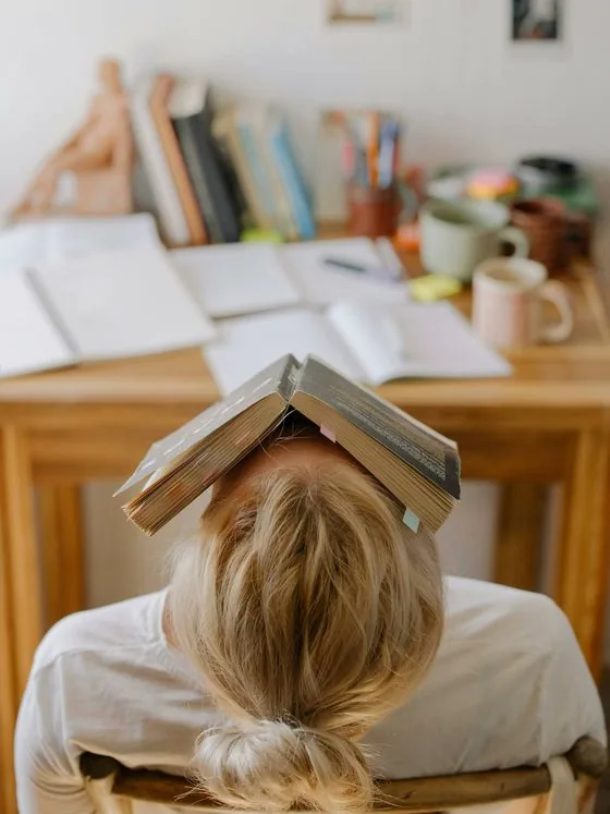 Estudiante con libro en la cabeza estudiando